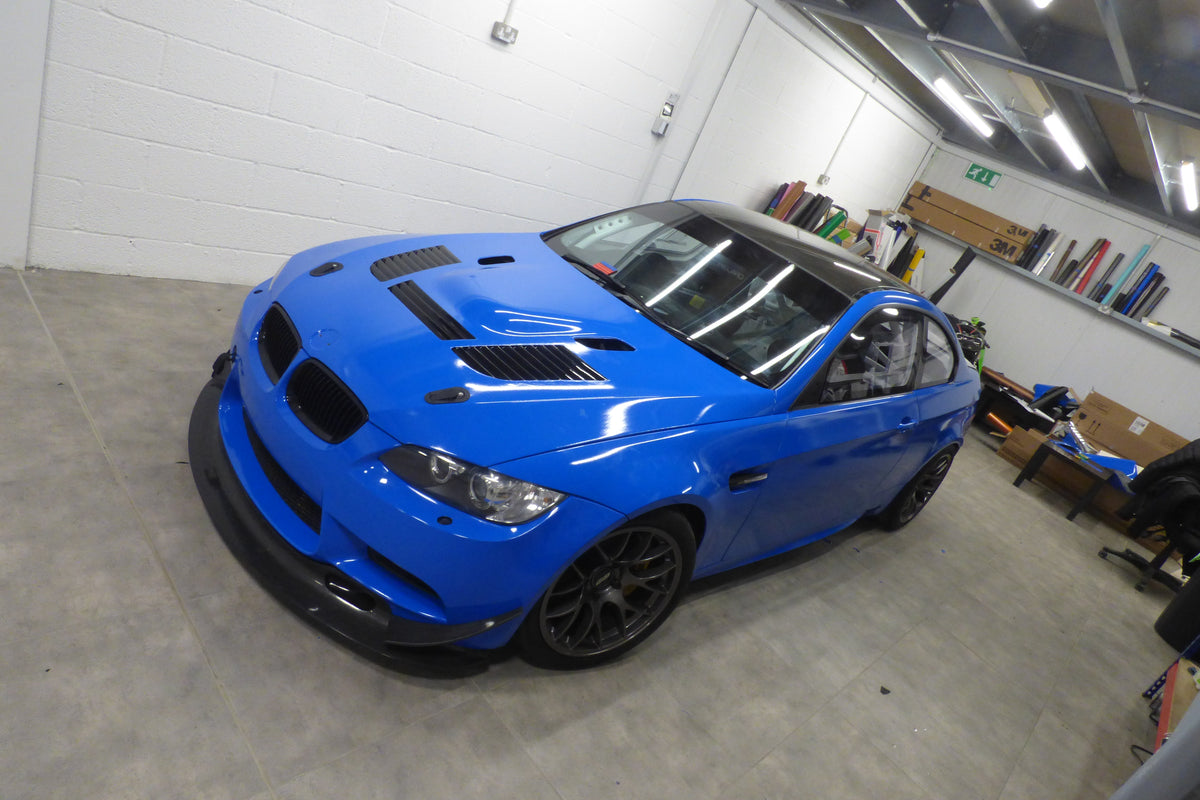 BMW M3 race car wrapped in 3M Gloss Blue by Wraptastic, front three-quarter workshop view